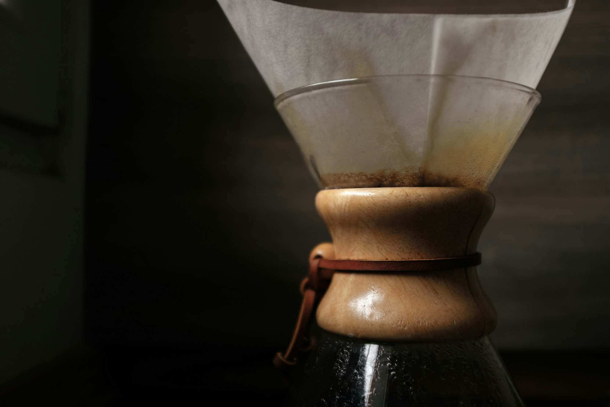 Café filtrándose en una cafetera de vidrio con collar de madera