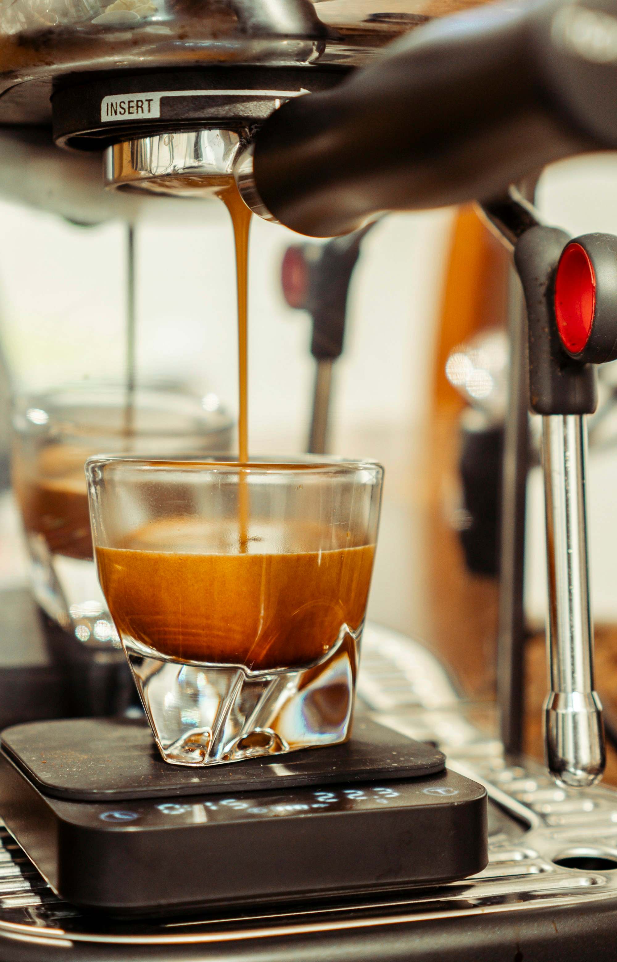 Espresso cayendo en un vaso de vidrio sobre una báscula