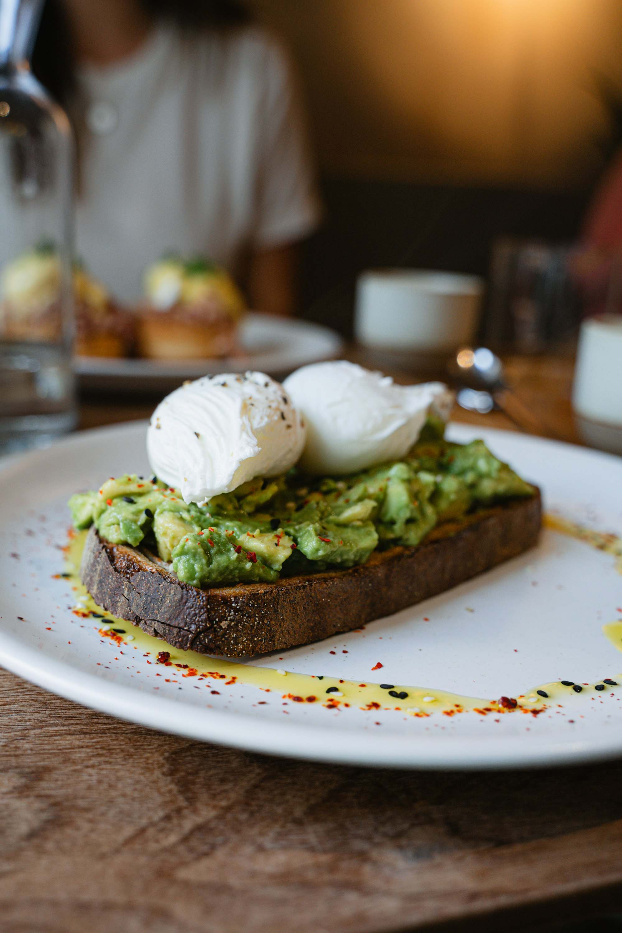 Pan de masa madre con aguacate y huevos pochados en un plato blanco